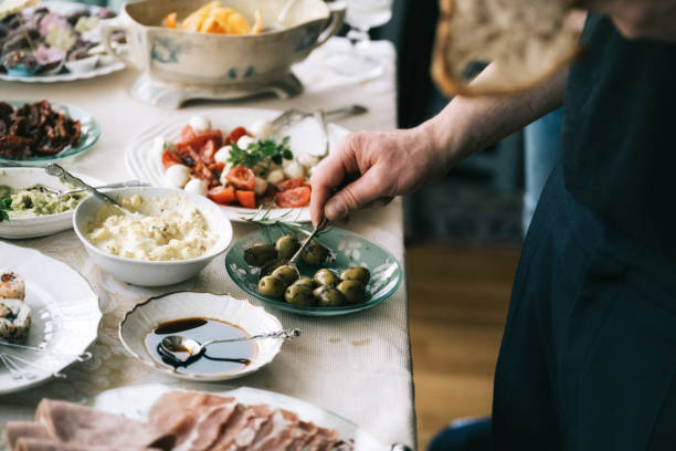 man taking antipasti from festive buffet close up of male hand taking green olives from brunch table mediterranean food stock pictures, royalty-free photos & images