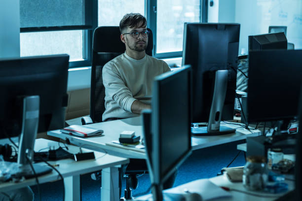 Programmer sitting at the desk in his office and trying to solve problem of new code.