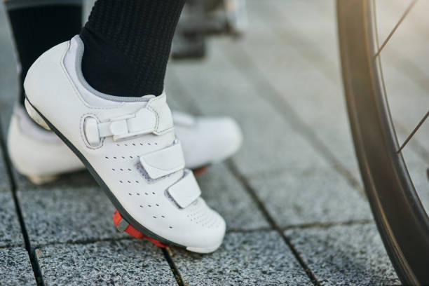крупным планом выстрел ноги женщины-велосипедистки носить велосипедные ботинки стоял со своим велосипедом - bicycle cycling bicycle pedal part of стоковые фото и изображения