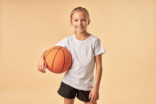 Portrait of active young 7 year's old Caucasian girl playing with a basketball ball