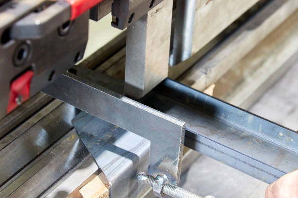 worker holding a metal part on sheet bending machine