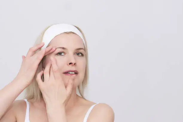 Photo of middle-aged woman makes self-massage of the face around the eyes, close-up portrait