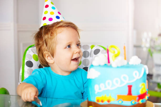 istock Toddler in party cap sit with birthday cake 1315448079