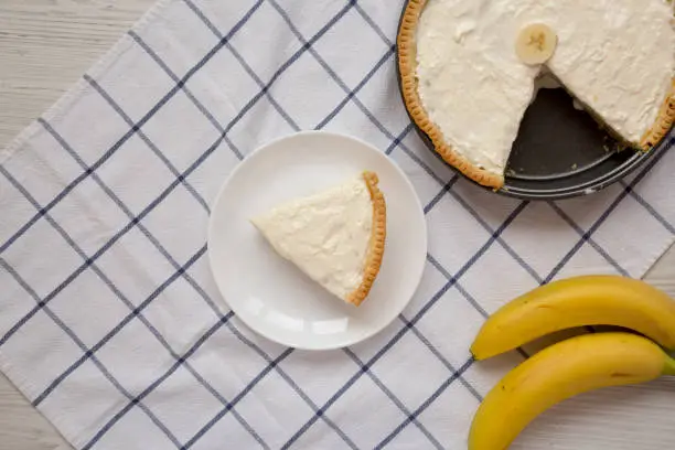 Homemade Tasty Banana Cream Pie on a white wooden background, top view. Flat lay, overhead, from above. Copy space.