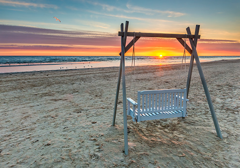 Sunrise and public swing on sandy beach of the Baltic Sea in Jurmala