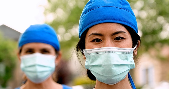 Sonrientes trabajadores sanitarios asiáticos y caucásicos con máscara protectora en la cara photo