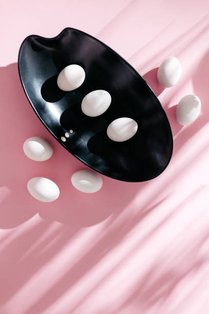 White eggs in black bowl on pink backdrop