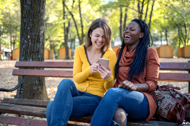 istock Multi ethnic friends in the autumn park have fun while using phone 1315460492