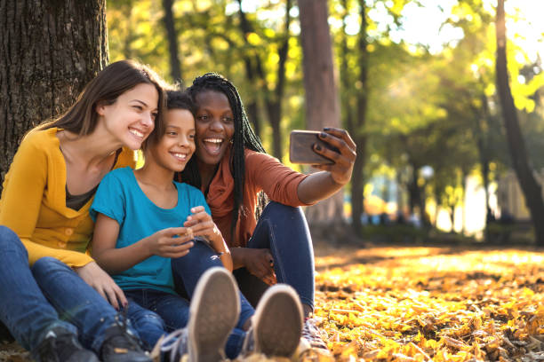 wielu etnicznych przyjaciół z dzieckiem robi selfie - mobile phone group of people photographing teenager zdjęcia i obrazy z banku zdjęć