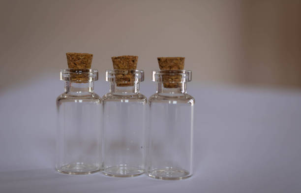 istock Three little empty glass bottles with corks on a a table, brown background 1315463247