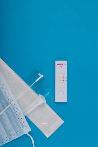 Rapid test for Covid-19 Coronavirus, positive result. Blue paper background, vertical orientation, copy space