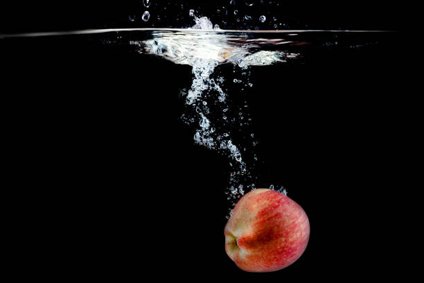 ripe red apple fell into the water with splashes on a black background, place under the test
