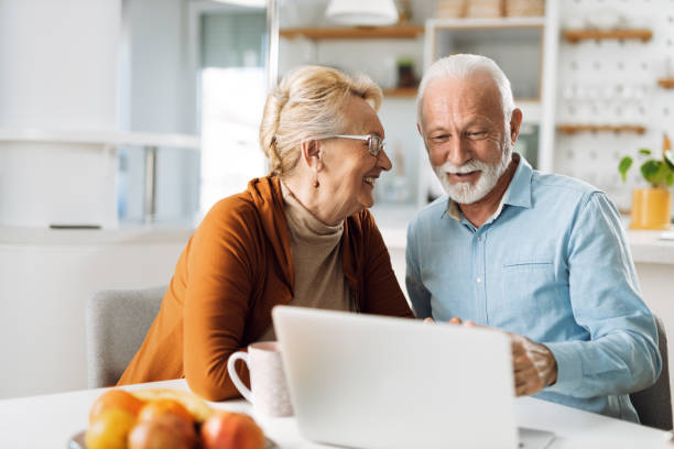 istock Cheerful  senior couple using laptop together at home 1315486152