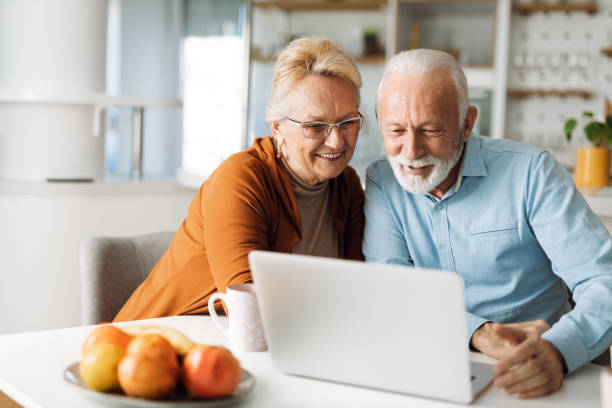 istock Cheerful  senior couple using laptop together at home 1315486408