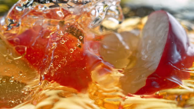 SLO MO LD Red apple wedges falling into juice