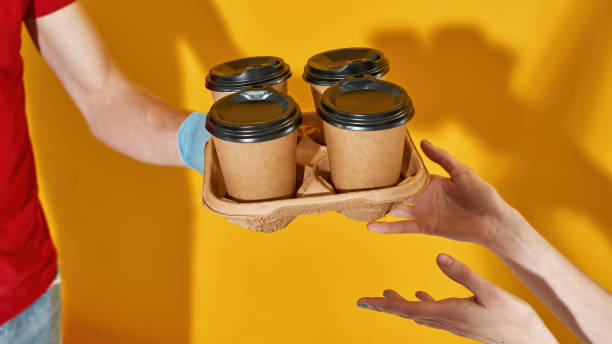 istock Deliveryman in protective gloves giving coffee cups 1315494403