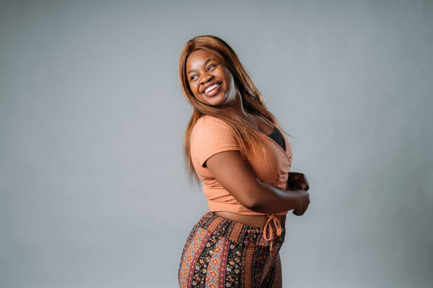 Portrait of a Beautiful, Confident, Fashionable African American Young Woman Laughing on a Gray Studio Background Portrait of a Beautiful, Confident, Fashionable African American Young Woman on a Gray Studio Background plus size woman fashion laughing stock pictures, royalty-free photos & images