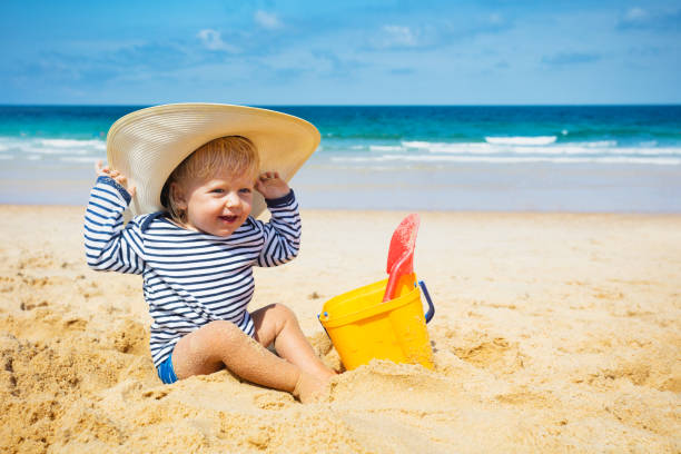 istock Little boy with huge straw hat sit on a sand beach 1315538047
