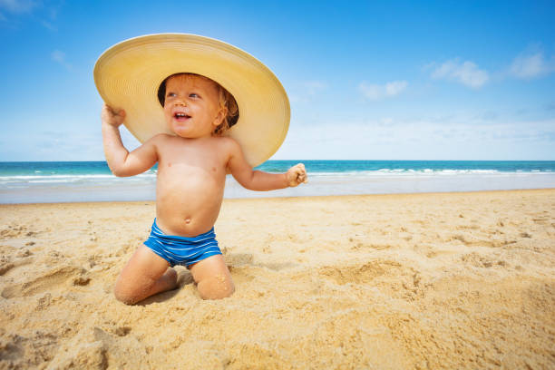 istock Little boy with huge straw hat sit on a sand beach 1315538050