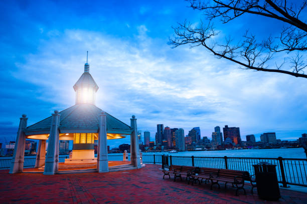 East Boston Pier Park Gazebo over downtown at dusk East Boston Piers Park Gazebo with lighthouse light in the evening over downtown panorama east boston stock pictures, royalty-free photos & images