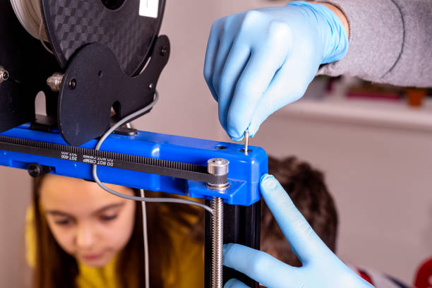 primer plano de la mano de un hombre con guantes azules calibrando una impresora 3d. - 3d printing fotografías e imágenes de stock