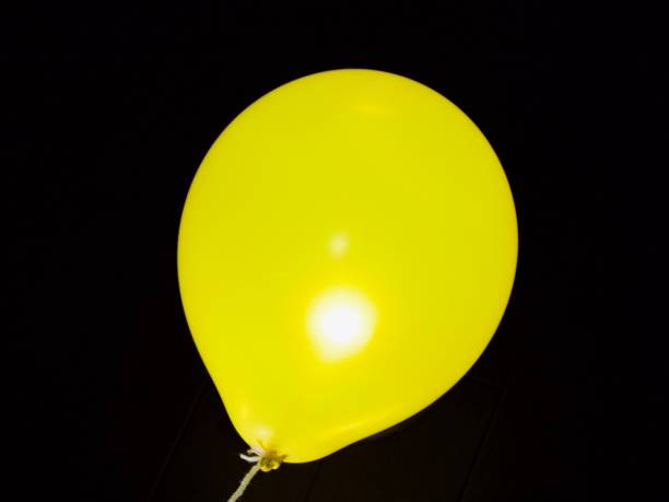 Close up horizontal image depicting many orange/yellow balloons of different shapes and sizes floating in a row. Room for copy space.