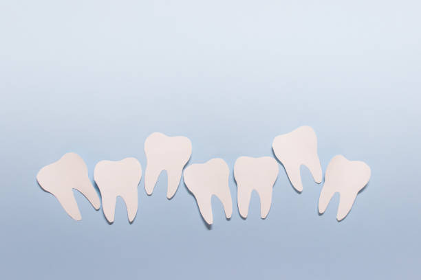 composition buccodentaire de stomatologie de papier avec la ligne inégale des dents sur le fond bleu - sweet tooth in a row photos et images de collection