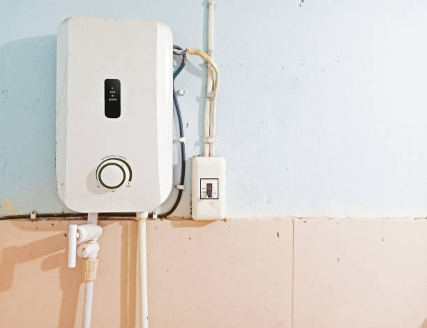 белый мгновенный водонагреватель установлен с выключателем на стене ванной комнаты с бесплатным пространством копирования. безопасность  - water heater стоковые фото и изображения