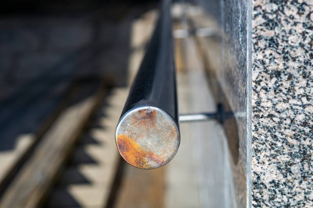 The beginning of a round metal railing on a granite wall