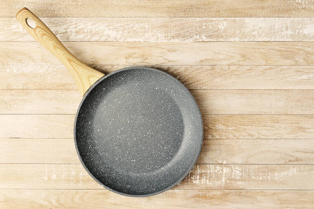 istock empty ceramic frying pan with wooden handle on wooden background 1315548455
