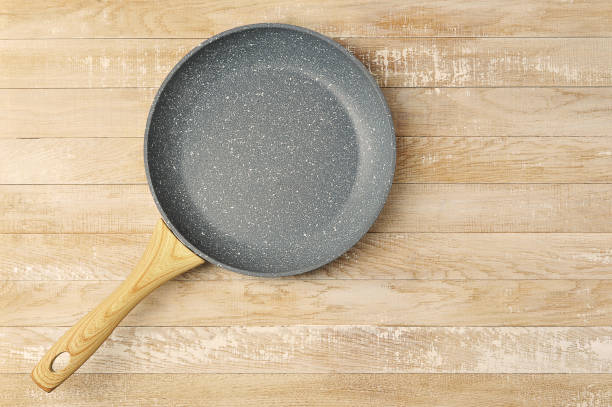 istock empty ceramic frying pan with wooden handle on wooden background 1315554134