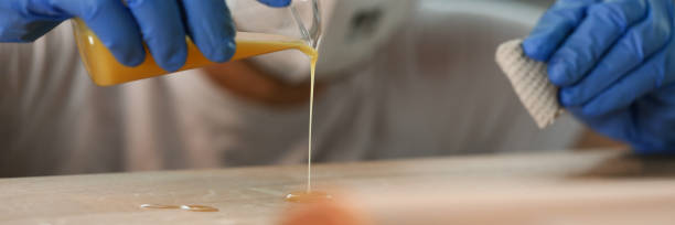 istock Gloved man pours yellow liquid tree, woodworking 1315556006