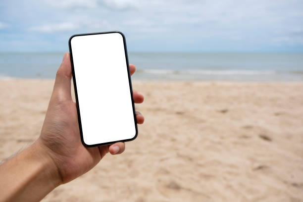 istock a man holding black mobile phone with blank desktop screen while standing on the beach 1315570877