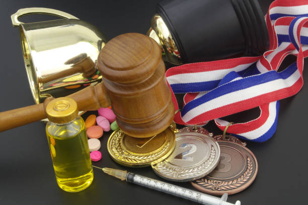 istock Broken golden winner cup with doping pills, syringe, medals and gavel as justice symbol on table 1315572195
