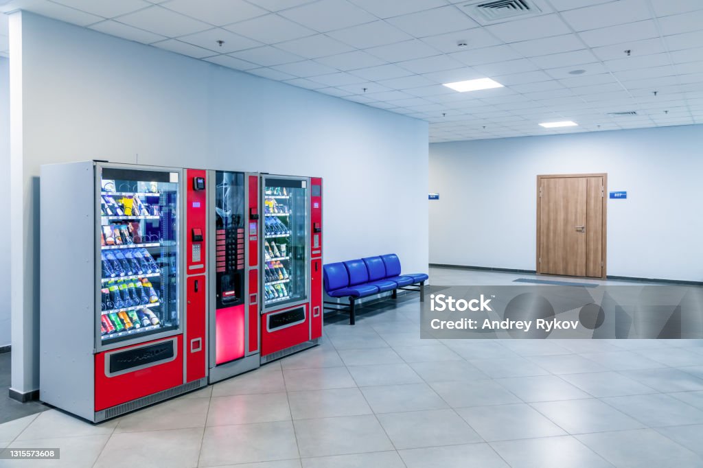 Vending machines in public building Group of red vending machines stands by the wall inside public building. No people. Unmanned store. Copy space for your text. Small business theme. Vending Machine Stock Photo