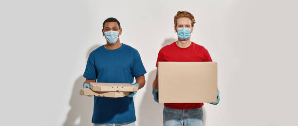 istock Mixed race couriers in gloves and masks holding boxes 1315575046