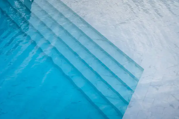 Photo of Swimming pool with transparent blue water and white marble luxury floor.