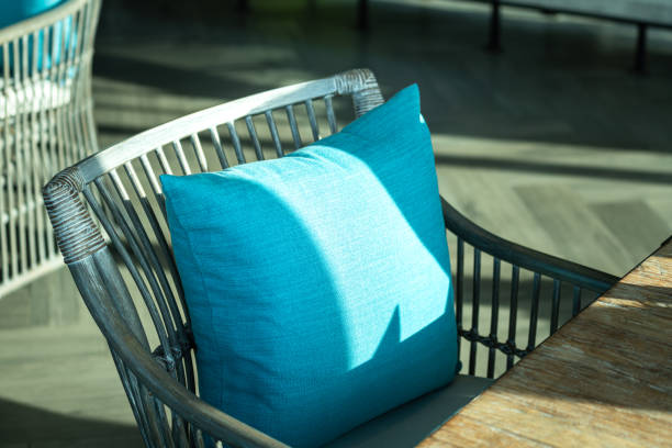 A bright blue color backrest pillow on cozy style seating furniture set. A bright blue color backrest pillow on cozy style chair and table set without people. Interior decoration object, close-up photo. backrest stock pictures, royalty-free photos & images