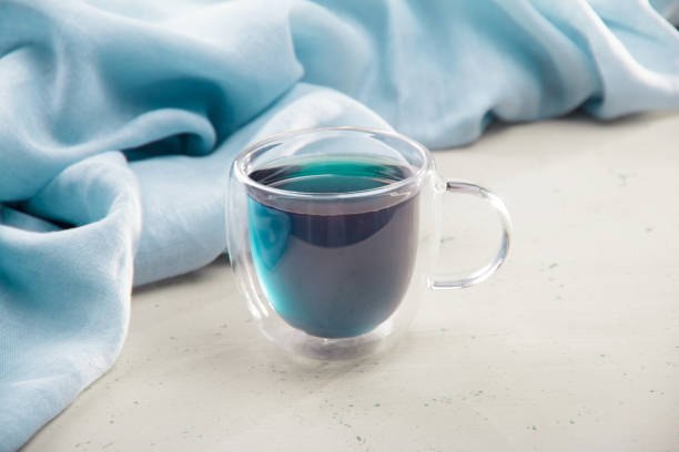 istock Blue tea in transparent cup with double bottom on light background and napkin 1315580195