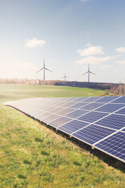 istock Photovoltaic park: Solar paneles with wind turbines and a warm blue sky. Renewable energies 1315581515