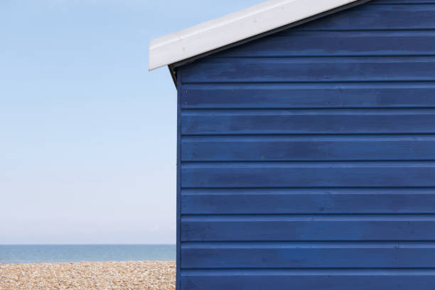 Deep blue coloured beach hut or shack with shingle and sea to side with space for copy
