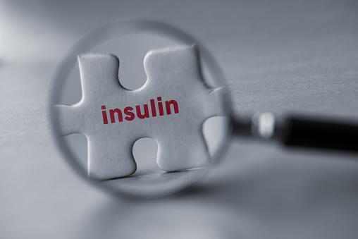 Magnifying glass and puzzle pieces with word insulin.