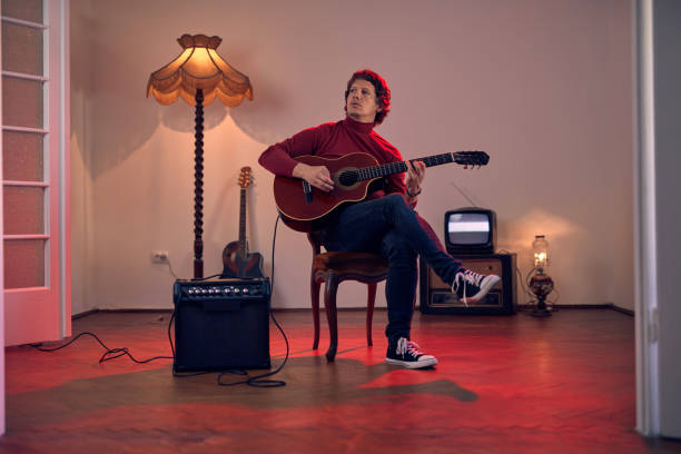 male musician playing acoustic guitar on the amplifier in retro vintage room. - fingerstyle imagens e fotografias de stock