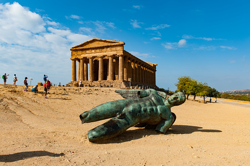 Temple of Concordia and the bronze statue of Icarus, the fallen angel, by Igor Mitoraj in the valley of temples near Agrigento on Sicily. Agrigento was one of the most important of the Greek colonies on Sicily.