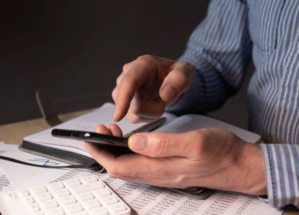 istock Businessman with mobile phone in hands and financial documents with numbers 1315606675