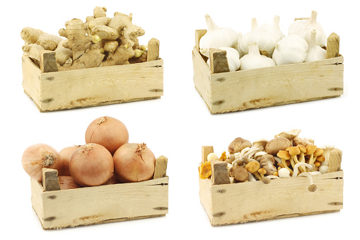 Assorted cooking vegetables in a wooden crate on a white background