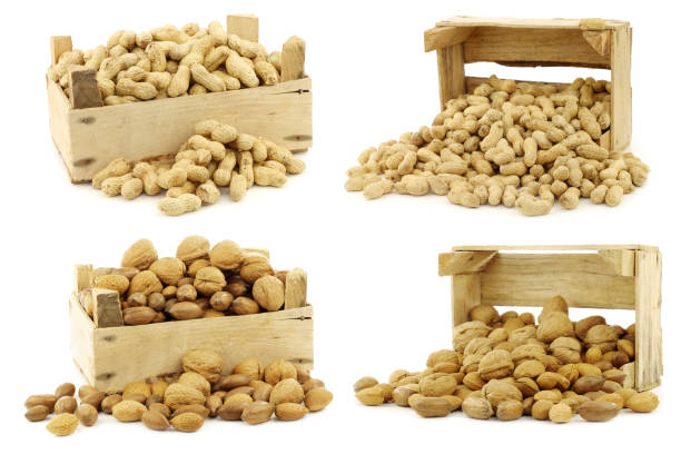 bunch of roasted peanuts and assorted other nuts  in a wooden box on a white background