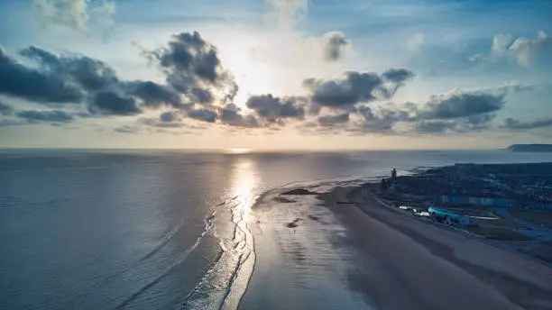 Drone view of sun over sea with small town of Coatham