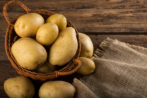 Fresh potatoes on the wooden table. Raw potatoes.