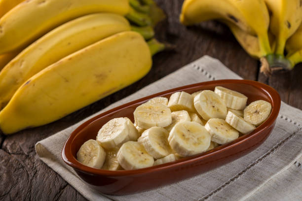 bündel bananen mit in scheiben geschnittenen bananen auf dem tisch - banana bunch yellow healthy lifestyle stock-fotos und bilder
